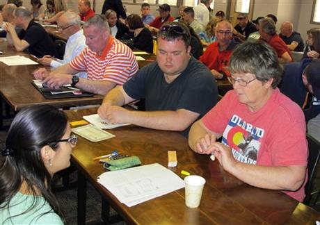 In this May 7, 2015 photo, trainer Elizabeth Terranova, left, instructs Diane Colby, right, and Stephen Colby, second from right, on how to use a nasal atomizer during a training session in Buffalo, N.Y., on how to administer naloxone, which...