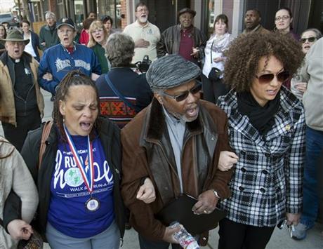 FILE - In this Friday, March 6, 2015, file photo, from left, Della Montgomery-Riggins, Charles Thornton and Spokane NAACP president Rachel Dolezal link arms and sing "We Shall Overcome" at a rally in downtown Spokane, Wash., responding to a racist...