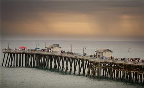 As storm clouds loom in the distance, lifeguards advise people to leave the pier and beach during the Ocean Festival in San Clemente, Calif. (Mindy Schauer/The Orange County Register via AP)