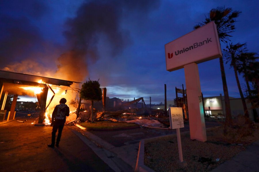 A man looks on as a bank burns after a protest over the death of George Floyd, Sunday, May 31, 2020, in La Mesa, Calif. (AP Photo/Gregory Bull)