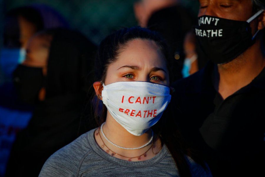 Madeline Curry attends a protest with her father outside the Minneapolis 5th Police Precinct while wearing a protective mask that reads "I CAN'T BREATHE" on Saturday. (AP Photo/John Minchillo)