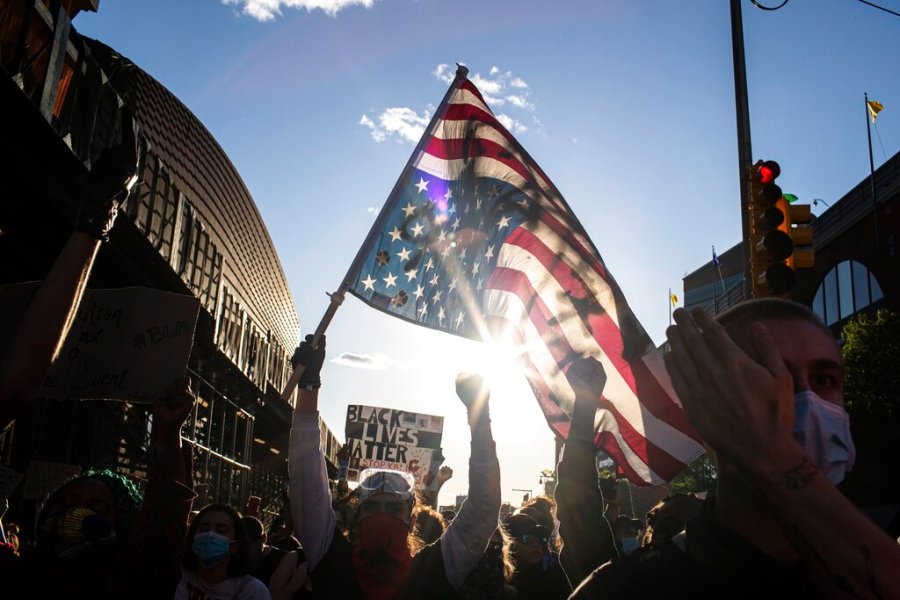 A man holds a U.S. flag upside down, a sign of distress, as protesters march down the street in the Brooklyn borough of New York. (AP Photo/Wong Maye-E)