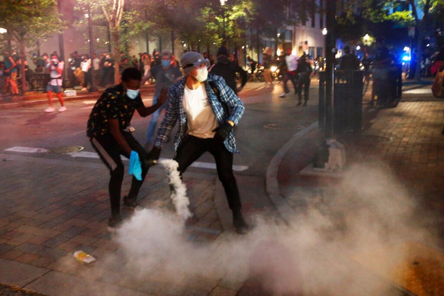 A protester tosses a smoke bomb towards police during a third night of unrest in Richmond, Va. The smoke bomb was ignited by a protester. (AP Photo/Steve Helber)