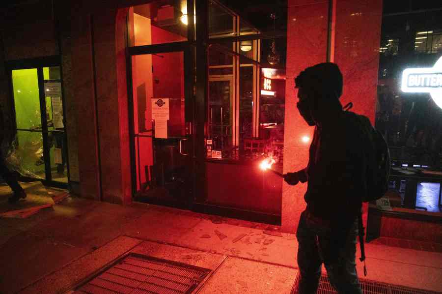 A person holds a burning flare near the entrance to a restaurant during a demonstration near the White House. (Photo by ROBERTO SCHMIDT/AFP via Getty Images)