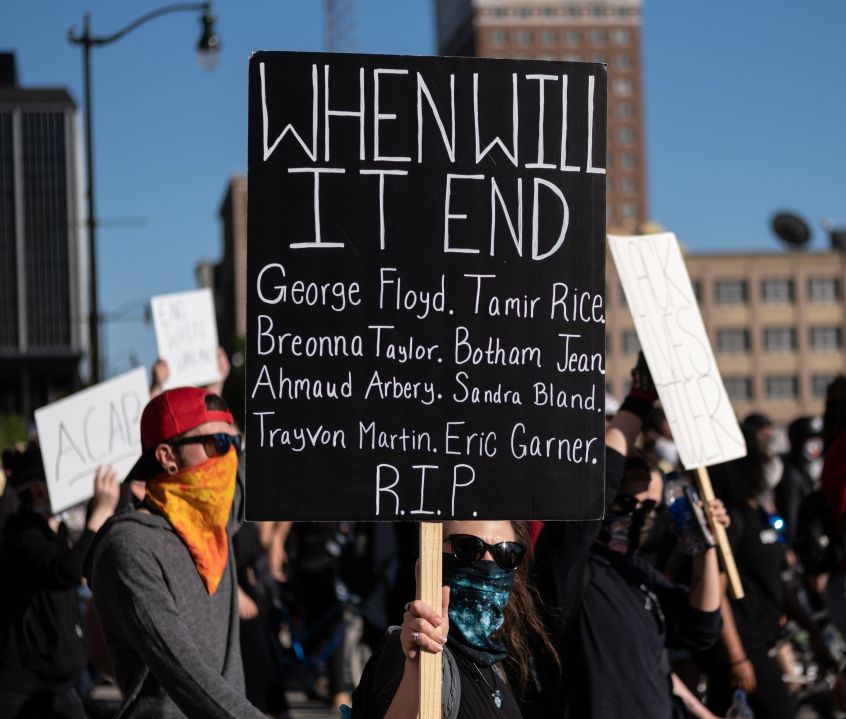 Protesters hold signs in Detroit, Michigan on May 31, 2020 following a night of protests that saw several arrests and use of tear gas by the Detroit Police department. (Photo by SETH HERALD/AFP via Getty Images)