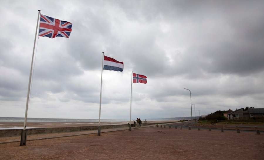 In this photo taken on Thursday, June 4, 2020, two people stop to look at an information board at Omaha Beach in Saint-Laurent-sur-Mer, Normandy, France. In sharp contrast to the 75th anniversary of D-Day, this year's 76th will be one of the loneliest remembrances ever, as the coronavirus pandemic is keeping nearly everyone from traveling. (AP Photo/Virginia Mayo)