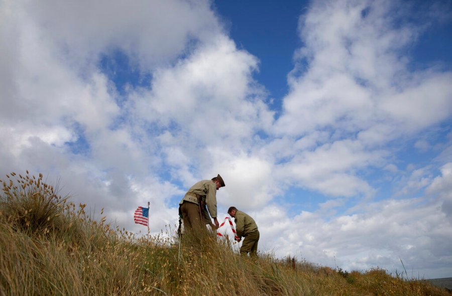 Two men in WWII period uniforms mark off an area in a dune overlooking Omaha Beach prior to a ceremony at the Charles Shay Memorial in Saint-Laurent-sur-Mer, Normandy, France, Friday, June 5, 2020. Saturday's anniversary of D-Day will be one of the loneliest remembrances ever, as the coronavirus pandemic is keeping almost everyone away, from government leaders to frail veterans who might not get another chance for a final farewell to their unlucky comrades. (AP Photo/Virginia Mayo)