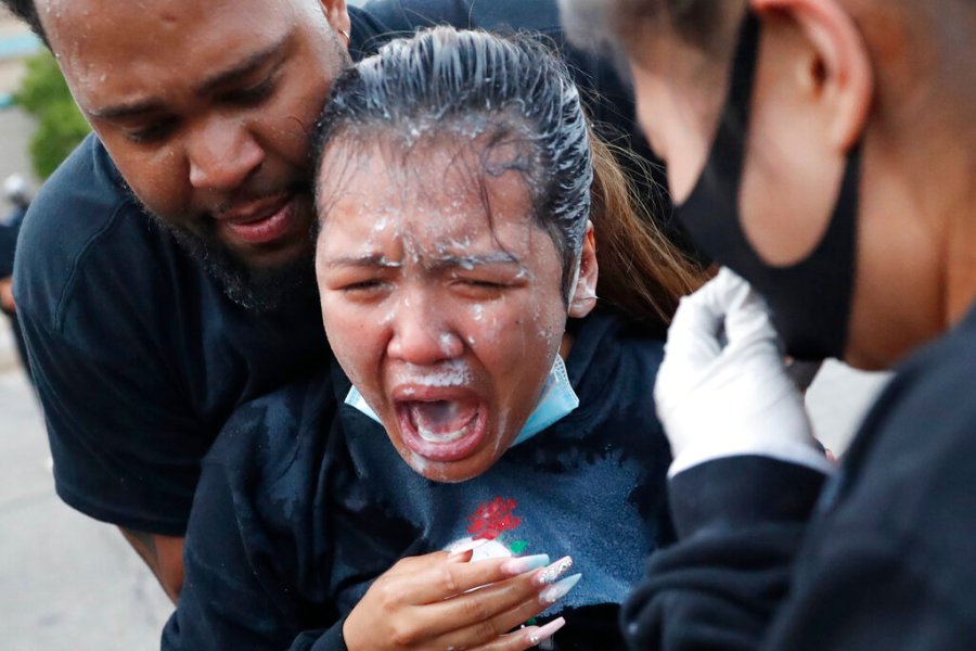 A woman is helped after being hit with pepper spray on Sunday in Minneapolis. (AP Photo/John Minchillo)