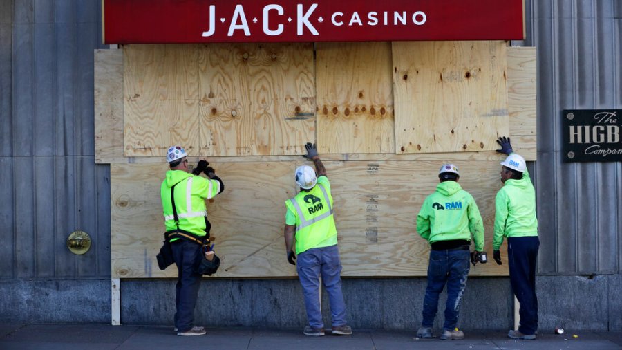 Workers install plywood over broken windows at Jack Casino in Cleveland. The City of Cleveland extended its curfew through Tuesday night after riots broke out on Saturday over the death of George Lloyd. (AP Photo/Tony Dejak)