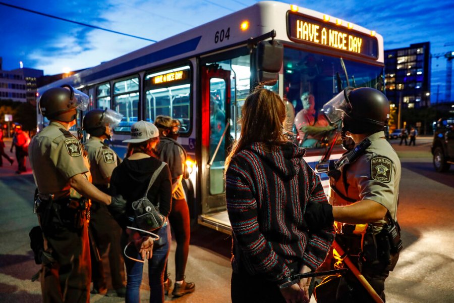 Arrested protesters are loaded onto a transport bus by police on South Washington Street in Minneapolis. (AP Photo/John Minchillo)